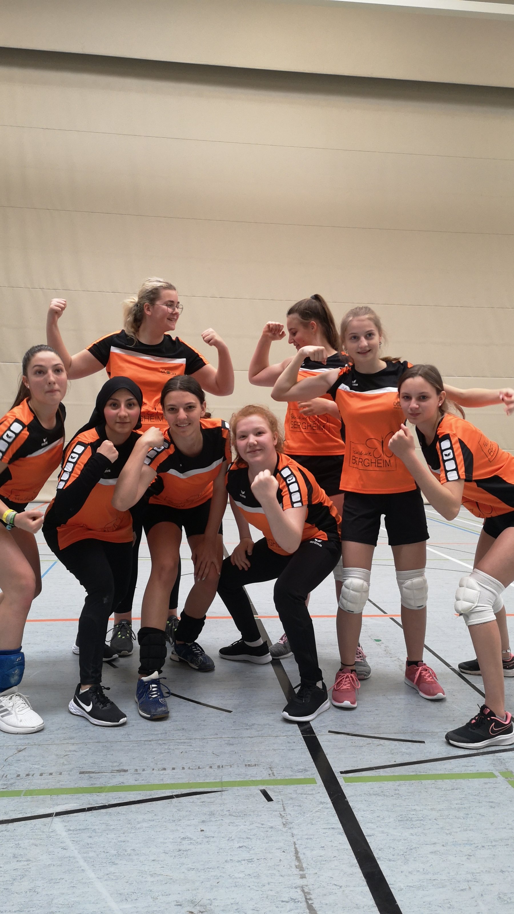 Mädchengruppe in orangen Volleyball-Dressen
