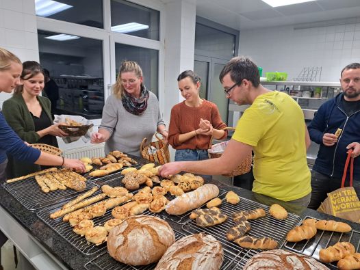 Abendschüler*innen teilen sich gebackenes Brot und Gebäck auf zum Mitnehmen